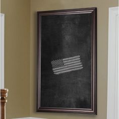 an american flag is hanging on the wall next to a framed chalkboard in a living room