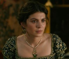 a woman in a green and gold dress is staring at the camera with an intense look on her face