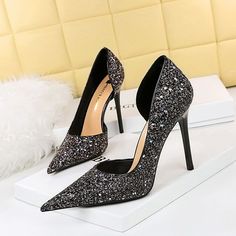 a pair of black glittered high heels sitting on top of a white box