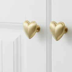 two gold heart shaped hooks on a white door