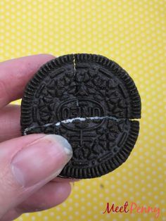 a hand holding an oreo cookie in front of a yellow background