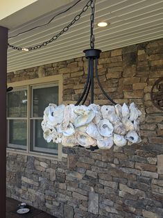 a chandelier made out of seashells hanging from a porch