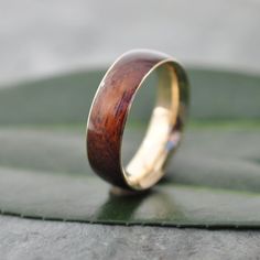 a wooden ring sitting on top of a green leaf