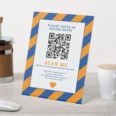 an orange and blue striped business card with a qr code on it next to a cup of coffee