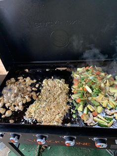 an outdoor grill with various vegetables cooking on it