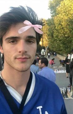 a young man with a pink bow on his head standing in front of a crowd