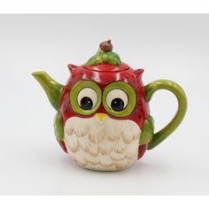 a ceramic owl teapot with eyes and a hat on it's head, sitting in front of a white background