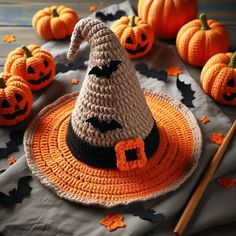 a crocheted witch hat sits on top of a table surrounded by pumpkins