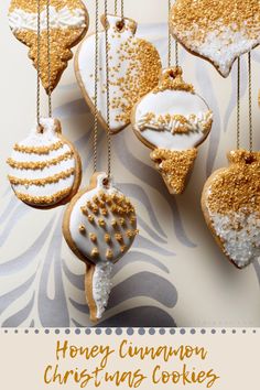 several decorated cookies hanging from chains on a tablecloth with gold and white ornaments in the shape of heart, christmas tree ornament