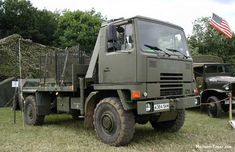 an army truck is parked in the grass