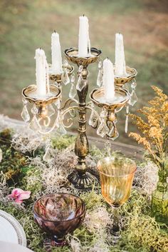 a table topped with candles and dishes covered in moss