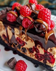 a piece of chocolate cheesecake with raspberries and chocolate sauce on the top