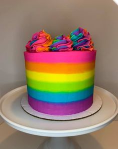 a rainbow cake with frosting and sprinkles on top