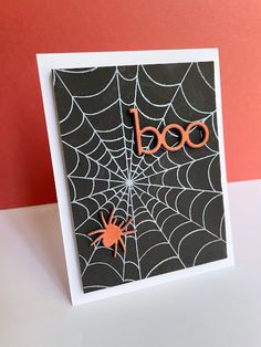 a card with the word boo on it and a spider web in front of it