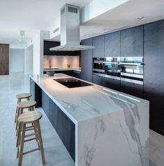 a kitchen with marble counter tops and stools