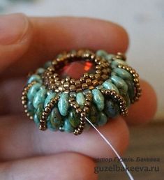 someone is holding a beaded ring in their left hand and needle through the middle