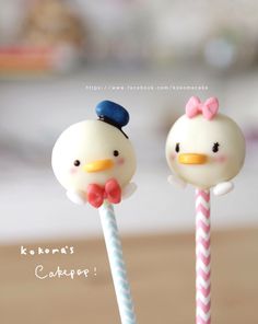 two lollipops in the shape of birds with bows on their heads are sitting next to each other