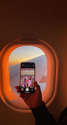 a person taking a photo with their cell phone on an airplane window