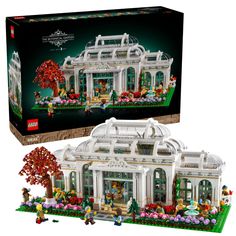 a lego set in the shape of a white house with lots of flowers and trees