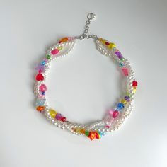 a multi - colored bracelet with beads and charms on a white surface, the bead is attached to a silver chain