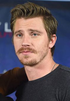 a close up of a person wearing a black shirt with a goatee and beard