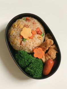 a black bowl filled with rice, broccoli and carrots on top of a white table