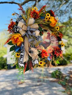 a wreath hanging from the side of a tree with sunflowers and other flowers