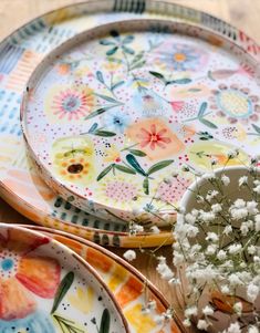 two plates with flowers on them sitting next to each other