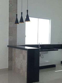 an empty kitchen with black counter tops and pendant lights hanging from it's ceiling