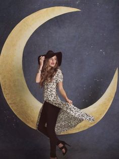 a woman is standing on the moon with her hat in her hand and she is wearing a leopard print dress