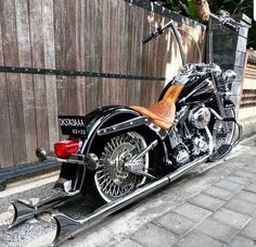 a black and brown motorcycle parked next to a wooden fence in front of a building