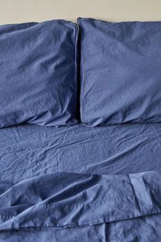 a bed with blue sheets and pillows on it