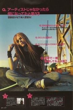 a woman sitting on the ground with long hair in front of her, wearing jeans and black