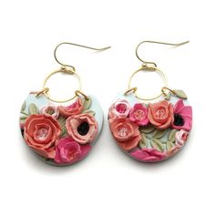 the earrings are decorated with pink flowers and gold hoop earwires on white background