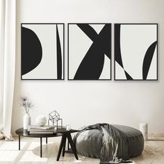 two black and white paintings hanging on the wall above a round table in a living room