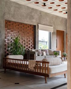 a living room filled with furniture and a brick wall next to a large potted plant