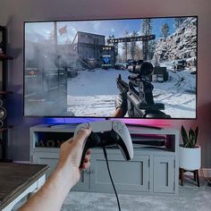 a person holding a video game controller in front of a flat screen tv