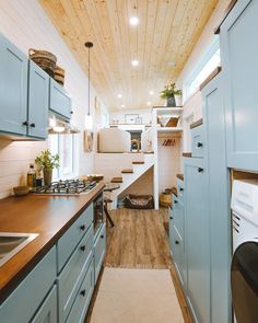 a narrow kitchen with blue cabinets and wood flooring