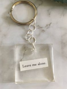 there is a keychain that says leave me alone on the glass block with a metal ring