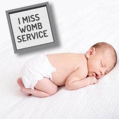 a baby laying on top of a bed next to a sign that says i miss womb service