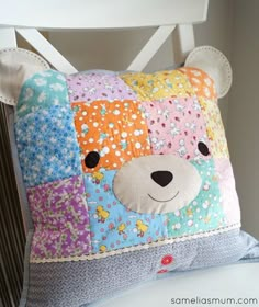 a colorful bear pillow sitting on top of a white chair