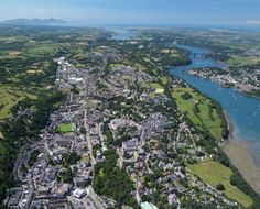 an aerial view of a city and river with lots of green land in the foreground