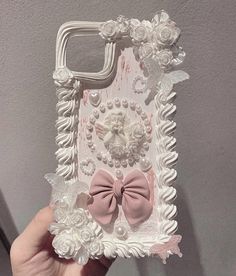 someone is holding up a phone case made out of flowers and pearls with a bow