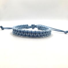 a bracelet with blue thread and beads on a white surface, the bead is attached to