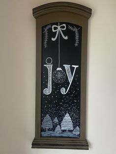 a clock with the word joy hanging from it's side in front of a white wall