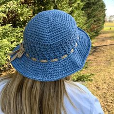 a woman wearing a blue crocheted hat with braids on the brim