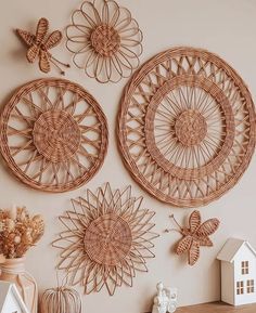 three wicker wall hangings on the wall above a wooden table with flowers and butterflies