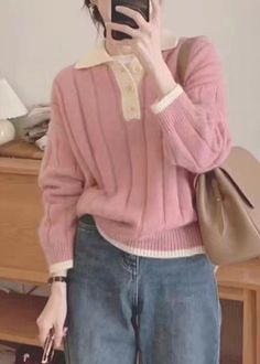 a woman is taking a selfie with her cell phone while wearing jeans and a pink sweater