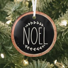 a black ornament hanging from a christmas tree with the word noel painted on it