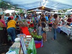 a group of people standing under a tent next to tables filled with food and drinks